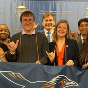 2025 UTSA Archer Fellows pose at graduation with their campus flag