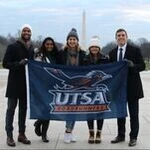A group of Archer Fellows hold a UTSA banner, the Washington Monument in the background.